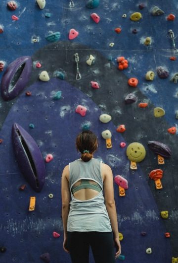 Woman staring up at climbing wall