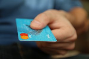 Person holding credit card. Stop doing these things if you're struggling with money.